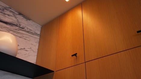 shot of modern sleek wood cabinets illuminated by a ceiling tube light, creating a stylish and well-lit kitchen ambiance