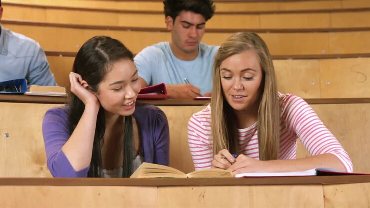 Klassekamerater som studerer på biblioteket og smiler til kameraet