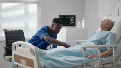 a black doctor of african appearance is talking to an elderly patient lying on the bed of the clinic. the cardiologist advises the patient. the neurologist conducted diagnostics