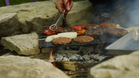 un hombre mueve los pimientos de una parrilla y en una sartén de hoja afuera