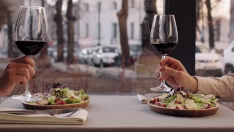 couple celebrating dinner with red wine and caesar salad