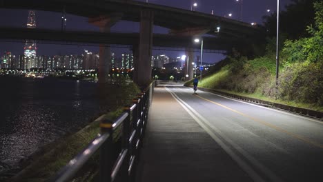 밤에 한국 서울 한강 근처 청담대교 아래를 지나가는 자전거 타는 사람 - 정적 광각 촬영