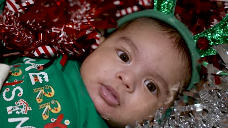 Joven-Adorable-Bebé-De-Dos-Meses-Con-Ropa-Festiva-Y-Adornos-Navideños-Con-Una-Camisa-Que-Dice-&quot;Feliz-Navidad&quot;-Con-Una-Diadema-De-Reno-Verde