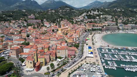 Old-town-center-of-Menton-with-Saint-Michel-Basilica-and-resort-area-in-Southern-France,-Aerial-dolly-out-shot