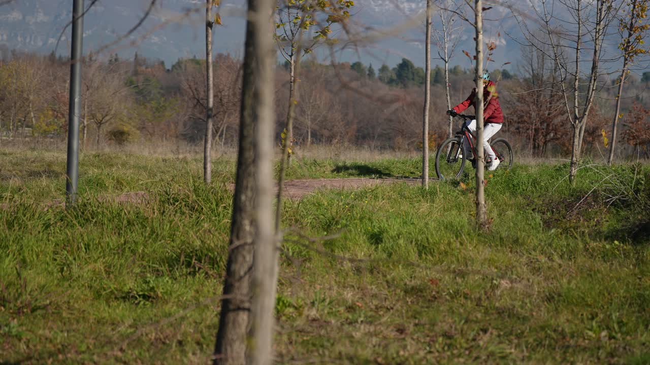 chica en bicicleta en el sendero del parque con casco de bicicleta de montaña, día soleado de invierno, deporte al aire libre felicidad en cámara lenta