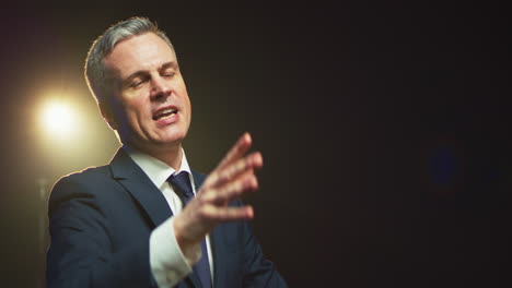 aggressive man speaking about politics from stage low angle of offensive male politician gesticulating and talking with audience from stage