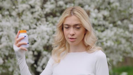 woman holding a pill bottle in a spring garden