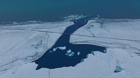 Aerial-landscape-view-over-the-shoreline-of-diamond-beach,-covered-in-snow,-at-dusk