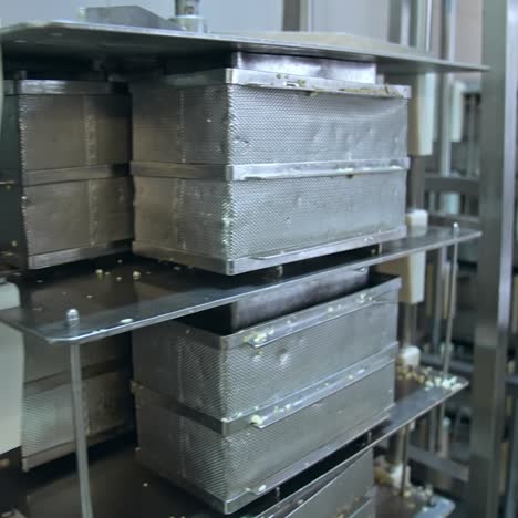 numerous stainless steel containers for butter. steel reticulated boxes for butter stored on the tall metal shelves. modern dairy enterprise