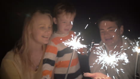 son and his parents catching sparkles of a bengale fire