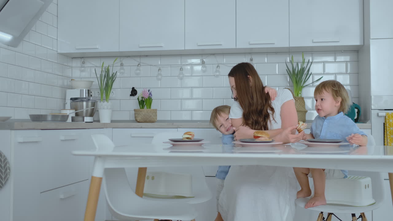 Mum with two young sons is eating burgers at home