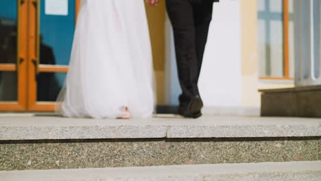 Woman-in-white-dress-and-groom-in-dark-suit-walk-to-stairs