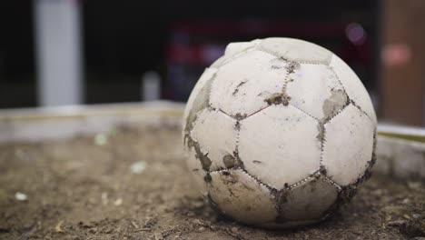 ragged and torn white football ball on the ground at night.