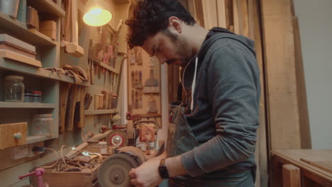 craftsman polishing metal detail with buffing machine in workshop