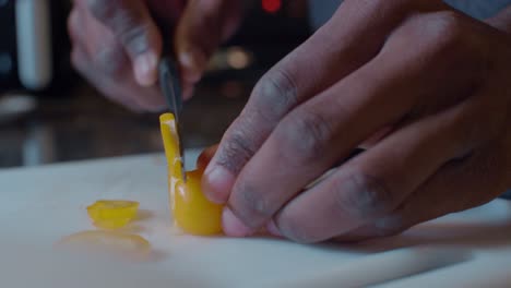 man slicing a cute small baby yellow bell pepper with small knife