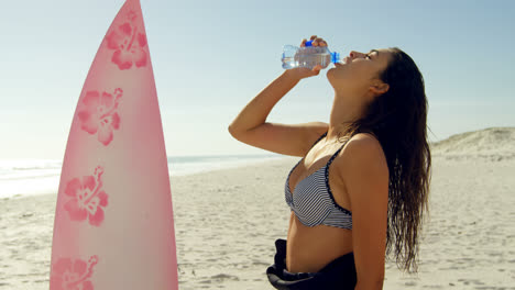 Surfista-Femenina-Bebiendo-Agua-En-La-Playa-4k-4k