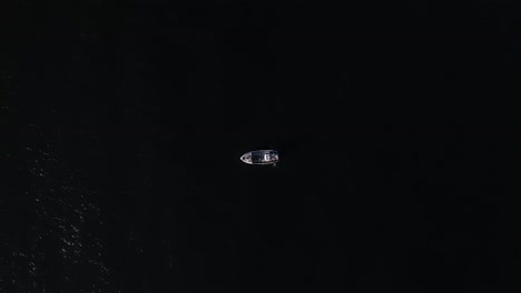 Drone-shot-of-a-fishing-boat-sailing-in-the-dark-vast-ocean