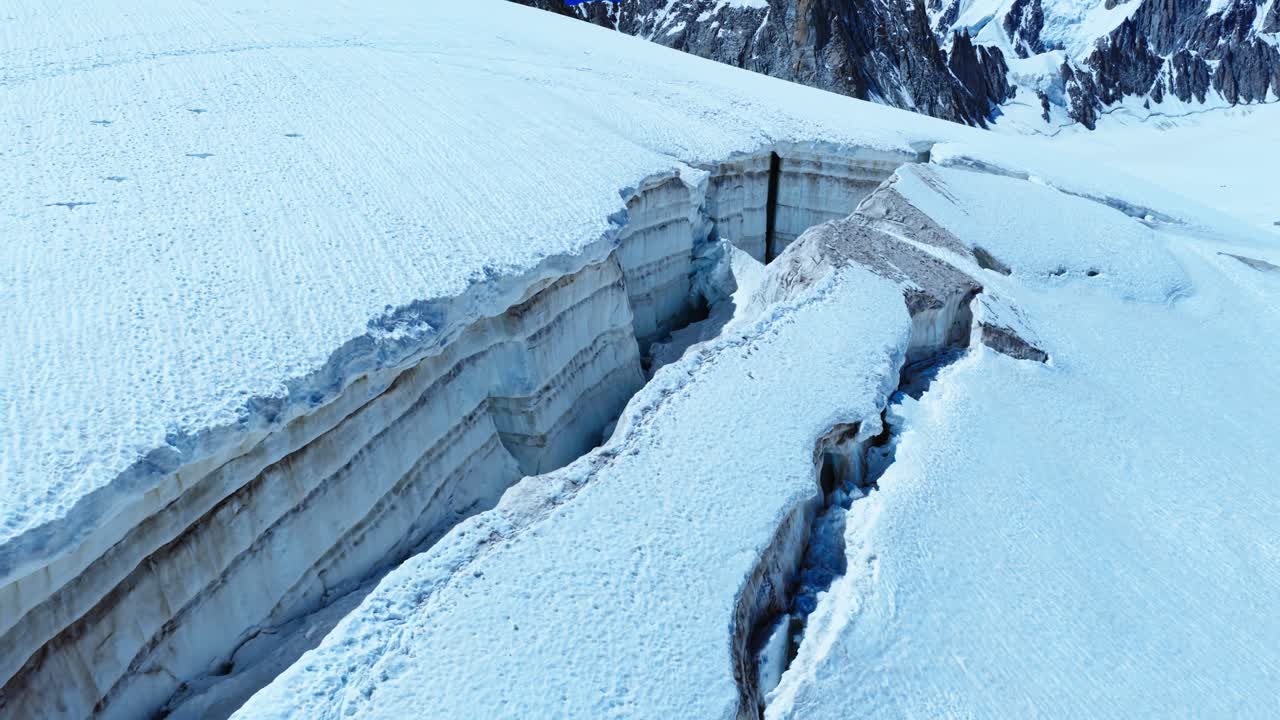 Masivní, hluboká trhlina v ledovcovém ledu Francouzských Alp poblíž Chamonix. Tato dramatická prasklina podtrhuje sílu přírody a vysokohorského klimatu, letecký pohled.