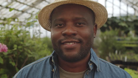 portrait of cheerful african american male farmer in greenhouse