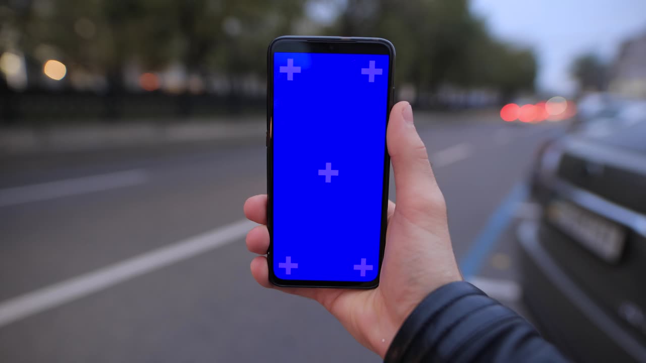 mano de hombre pobre sosteniendo una maqueta de pantalla vacía de un teléfono inteligente en la carretera de la ciudad