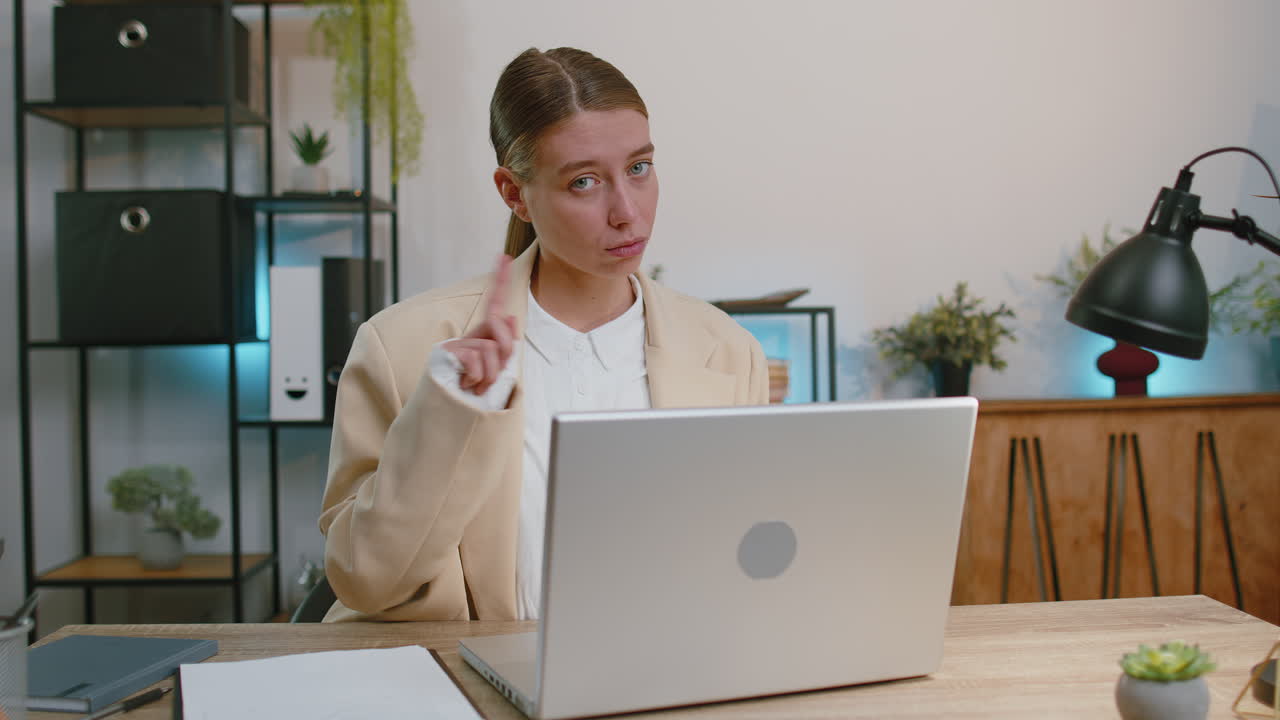 mujer de negocios que trabaja en la computadora portátil agita el dedo, diciendo no, tenga cuidado dando consejos para evitar errores