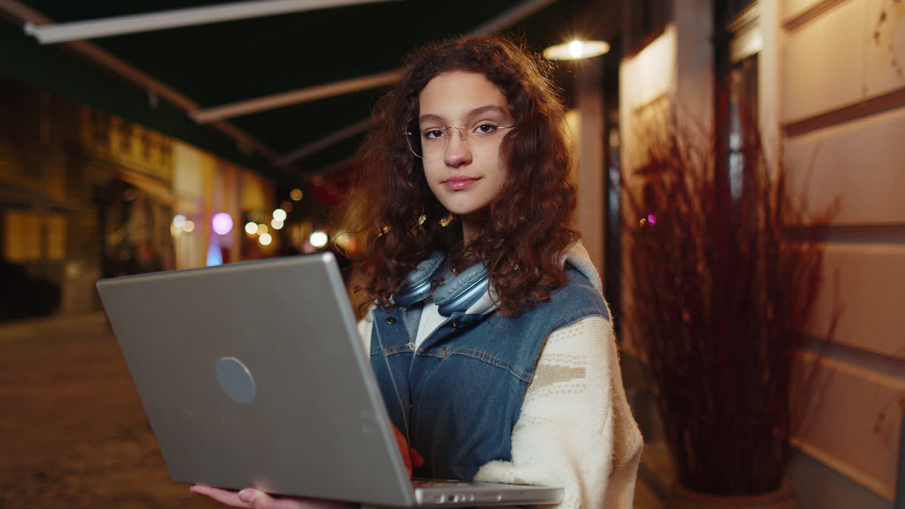chica sonriente trabajando en línea trabajo lejano con portátil en la ciudad calle navegando por el sitio web chateando