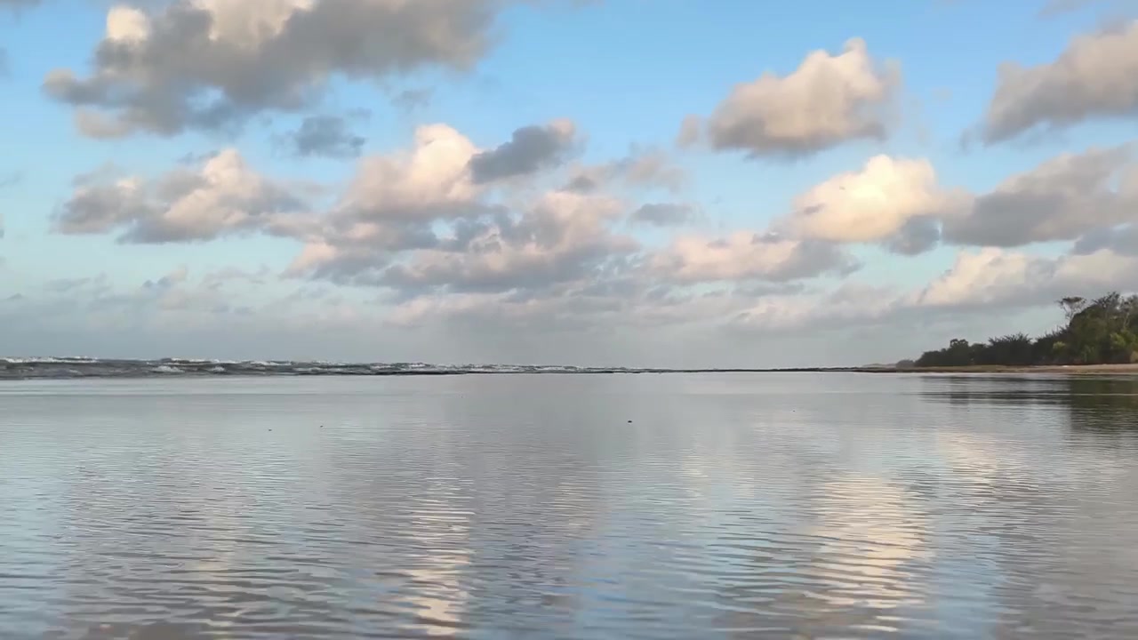 Onde marine calme che si adagiano dolcemente su una spiaggia sabbiosa al tramonto