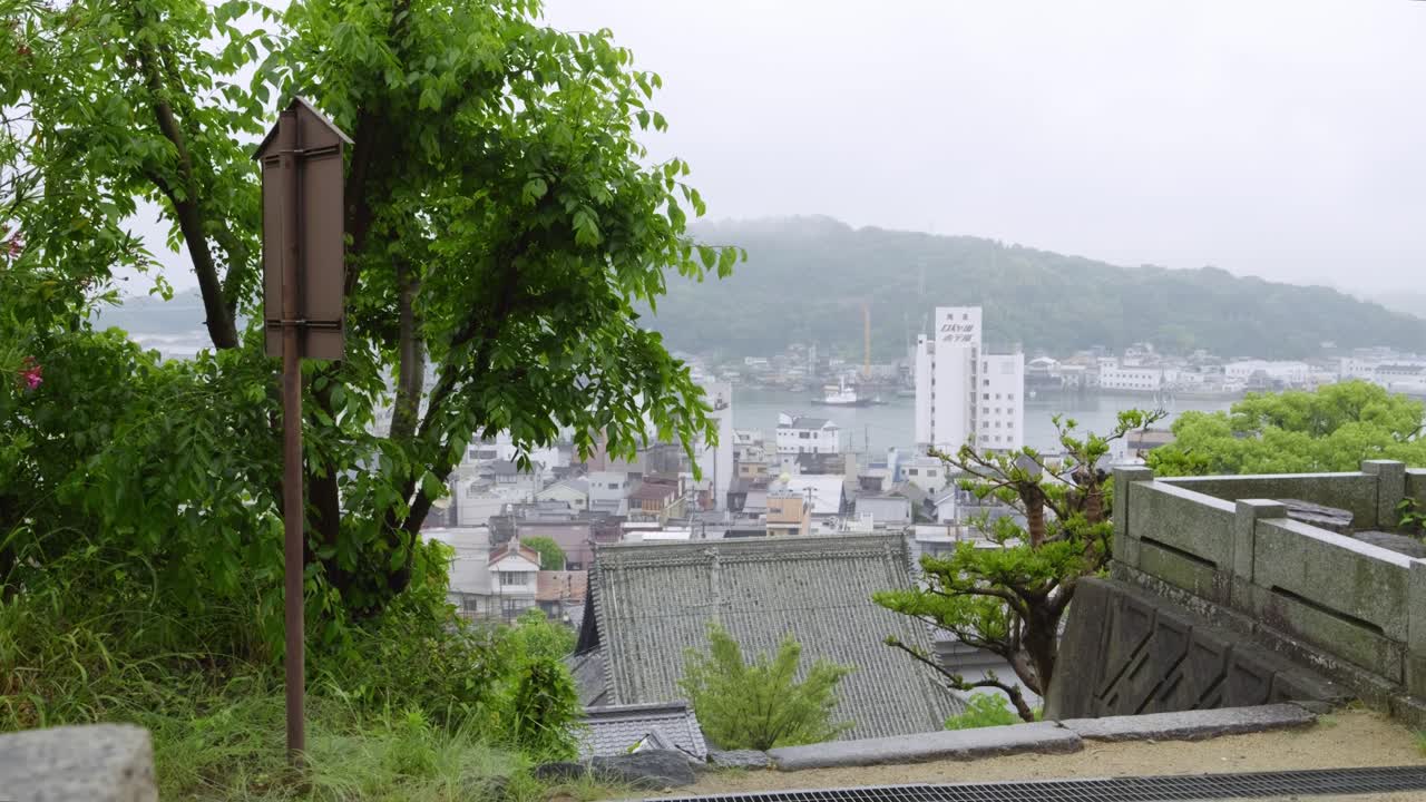 Stunning slow motion sideways slider reveal over Onomichi cityscape on rainy day