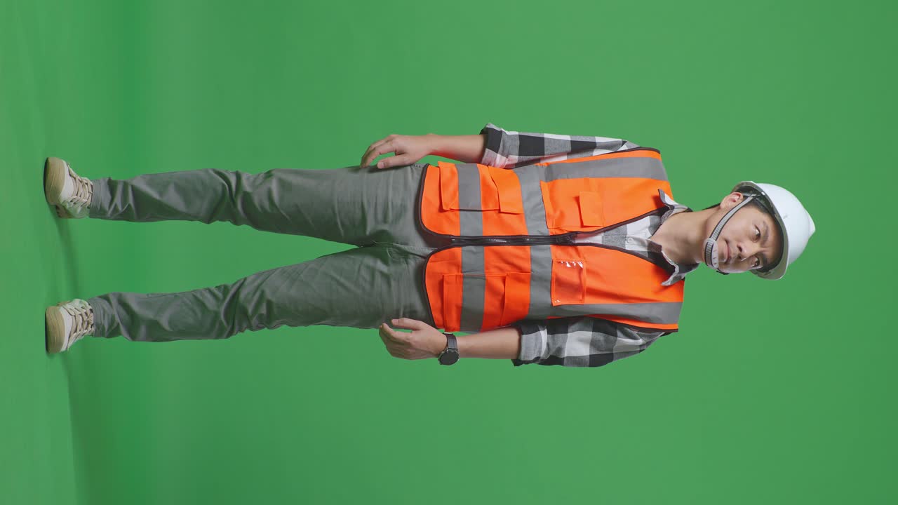Full Body Of Asian Male Engineer With Safety Helmet Looking Around While Standing In The Green Screen Background Studio