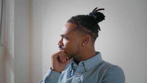 stressed hipster clutching head in office closeup. nervous guy looking window