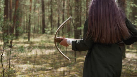 purple haired teen girl holds crossbow walking across wood