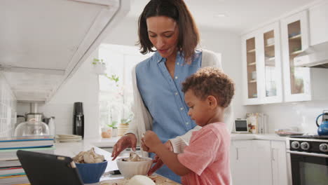 madre milenaria y hijo pequeño preparando comida juntos en la cocina, vista lateral, de cerca