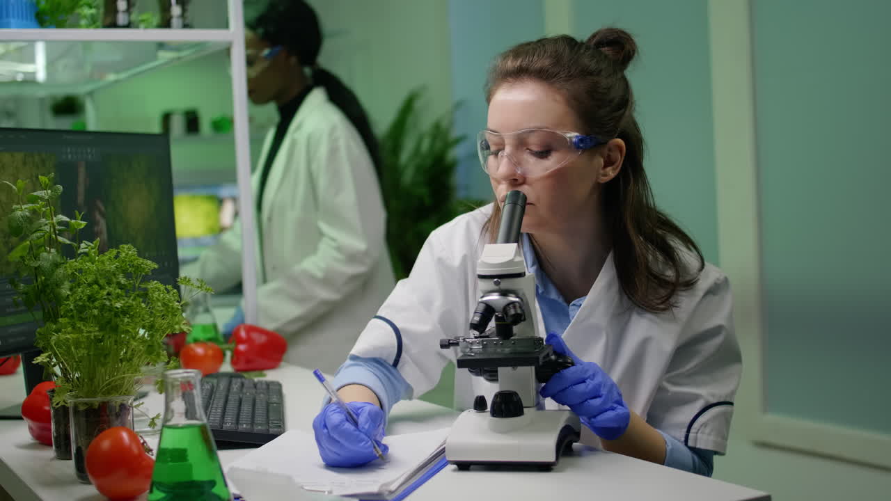 Biologist scientist looking at leaf sample using medical microscope