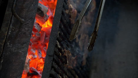 slow motion of a cook wearing black gloves turning around juicy beef meat steaks on a grill using grill tongs