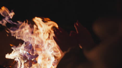 person warming their hands over a campfire