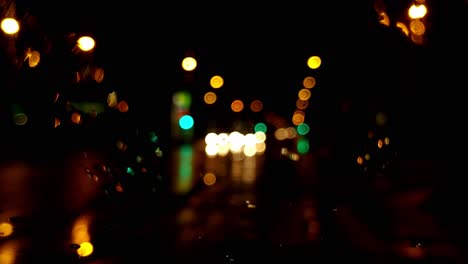 rainy night on bus, blurred street lights in city through window