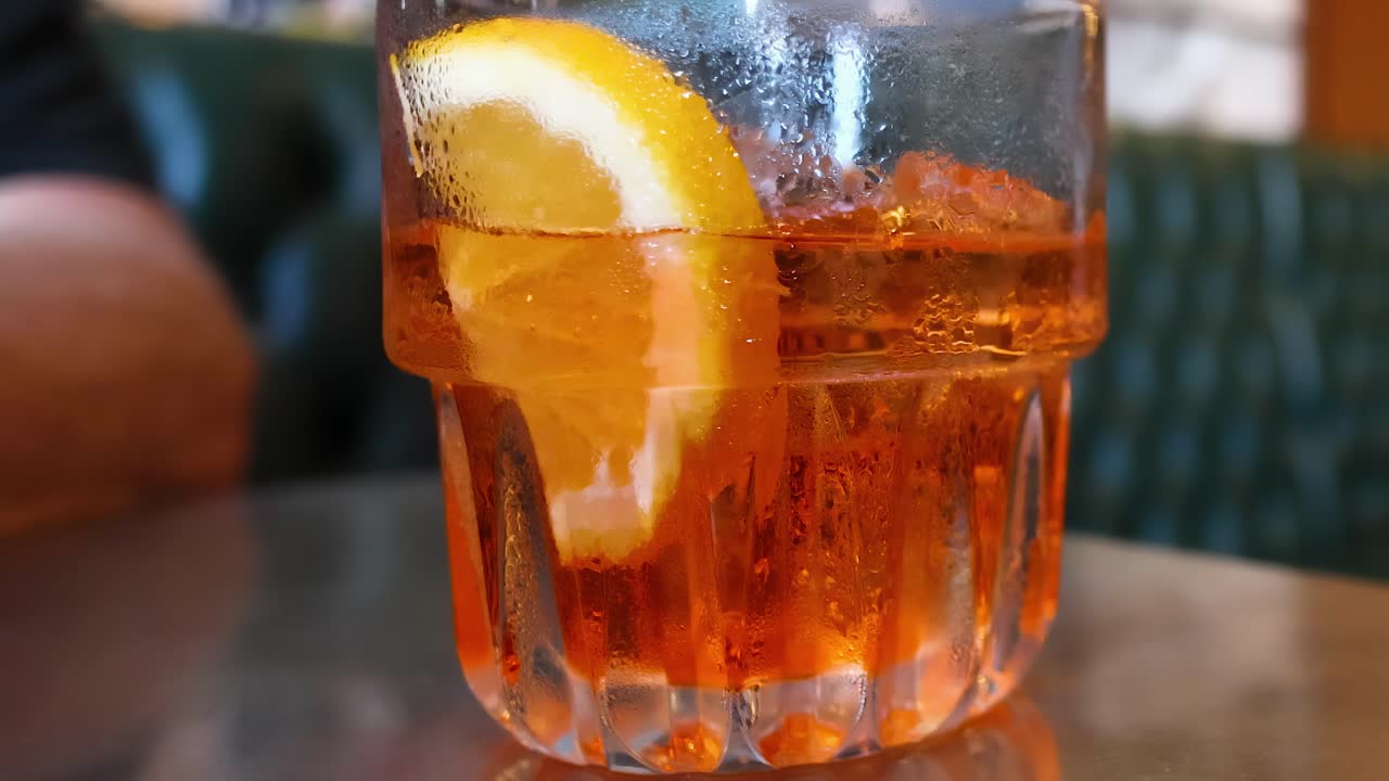 A close-up view of a sparkling orange drink with a slice of citrus on a cafe table.