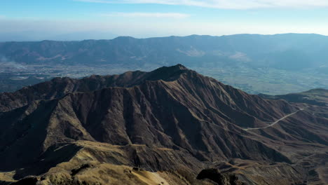 Drone-shot-passing-person-standing-on-the-peak-of-a-mountain-near-the-volcano-Mount-Aso