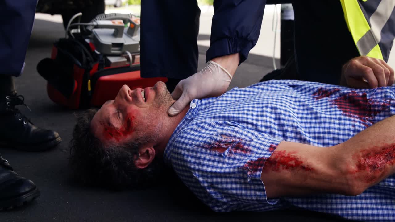 Emergency medical technician taking the pulse of injured man