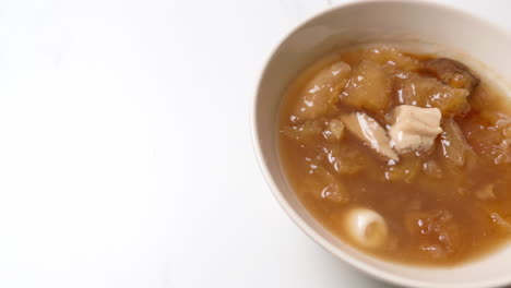 sliding from the right to the left side of the frame on a bowl filled with fish maw soup, a traditional and healthy asian dish served in southeast asian countries