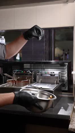 chef seasoning food in restaurant kitchen