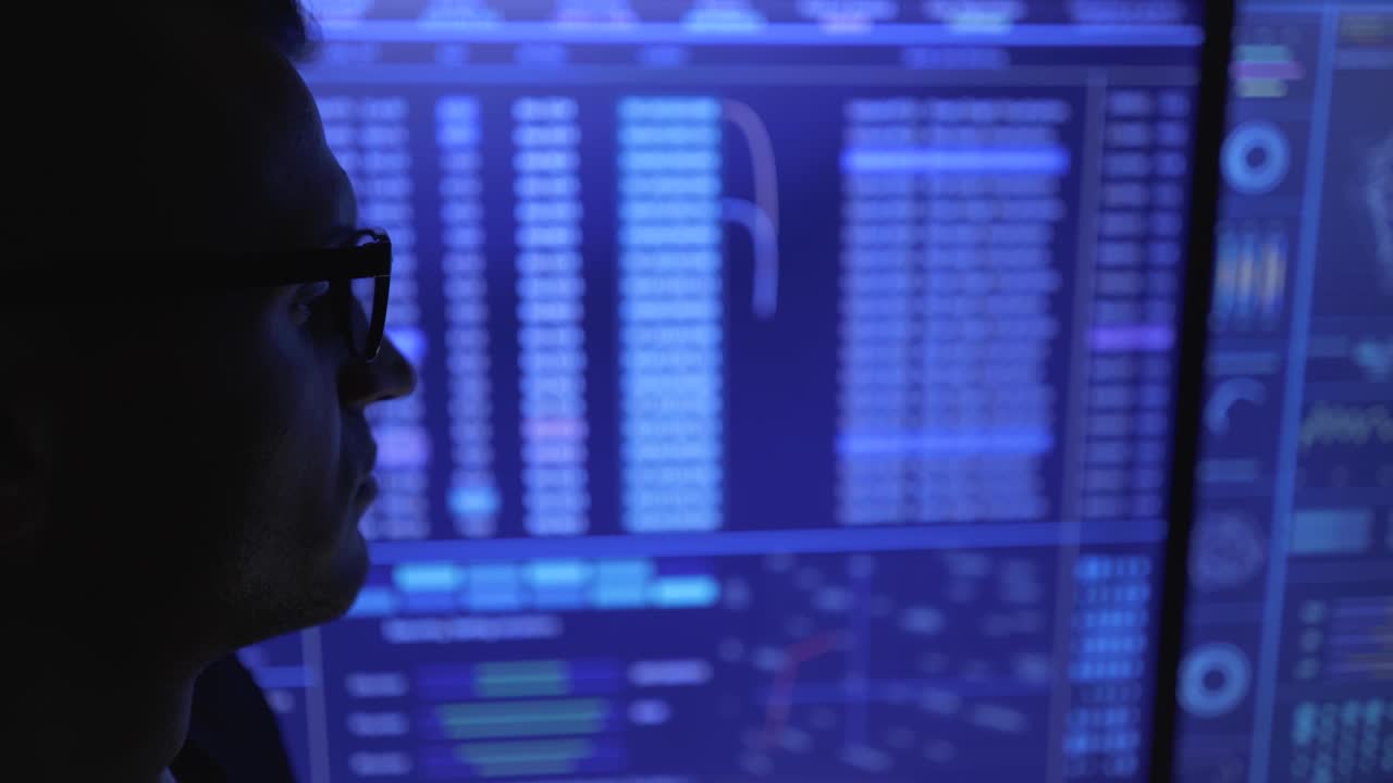 The male looking on the blue screen in the dark space