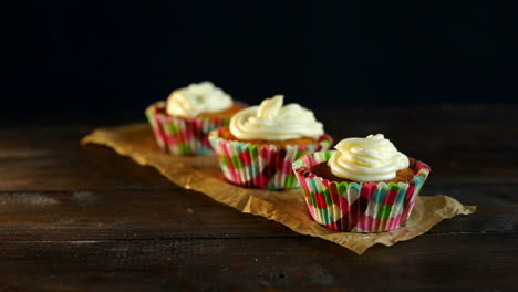 muffins with cake cream on baking paper. hand put cupcake on table