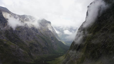 Winding-road-passing-thru-the-mountains,-fog,-and-clouds-in-Milford-Sound-New-Zealand-on-the-South-Island