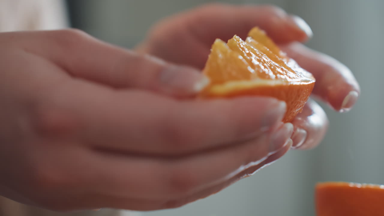 Gomo de fruta em iluminação quente. Vista íntima de mãos segurando laranja suculenta perto de xícara de café. Imagem detalhada mostrando mãos segurando delicadamente um gomo de laranja suculento em luz ambiente quente