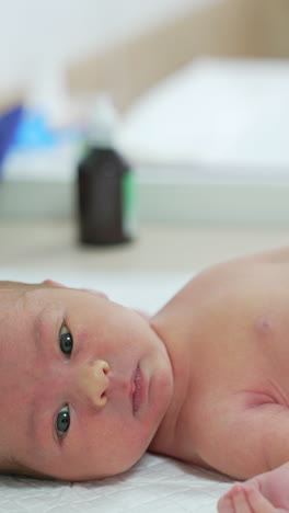 doctor performs medical procedure to an infant. newborn baby lying on hospital table. doctor uses modern medical appliance for treating baby in clinic.. vertical video
