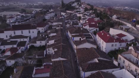 Flying-low-over-touristic-medieval-town-Obidos-with-no-people-at-sunrise,-aerial