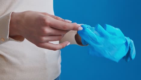 woman putting on blue medical gloves