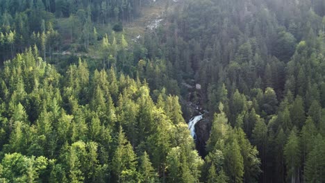 Aerial-flying-forward-reveals-hidden-Gollinger-waterfall-through-trees,-Austria