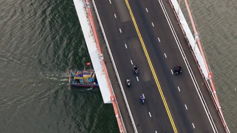 traditional boat pass under bridge with traffic